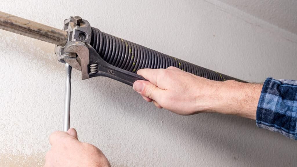 A technician repairing a broken garage door spring