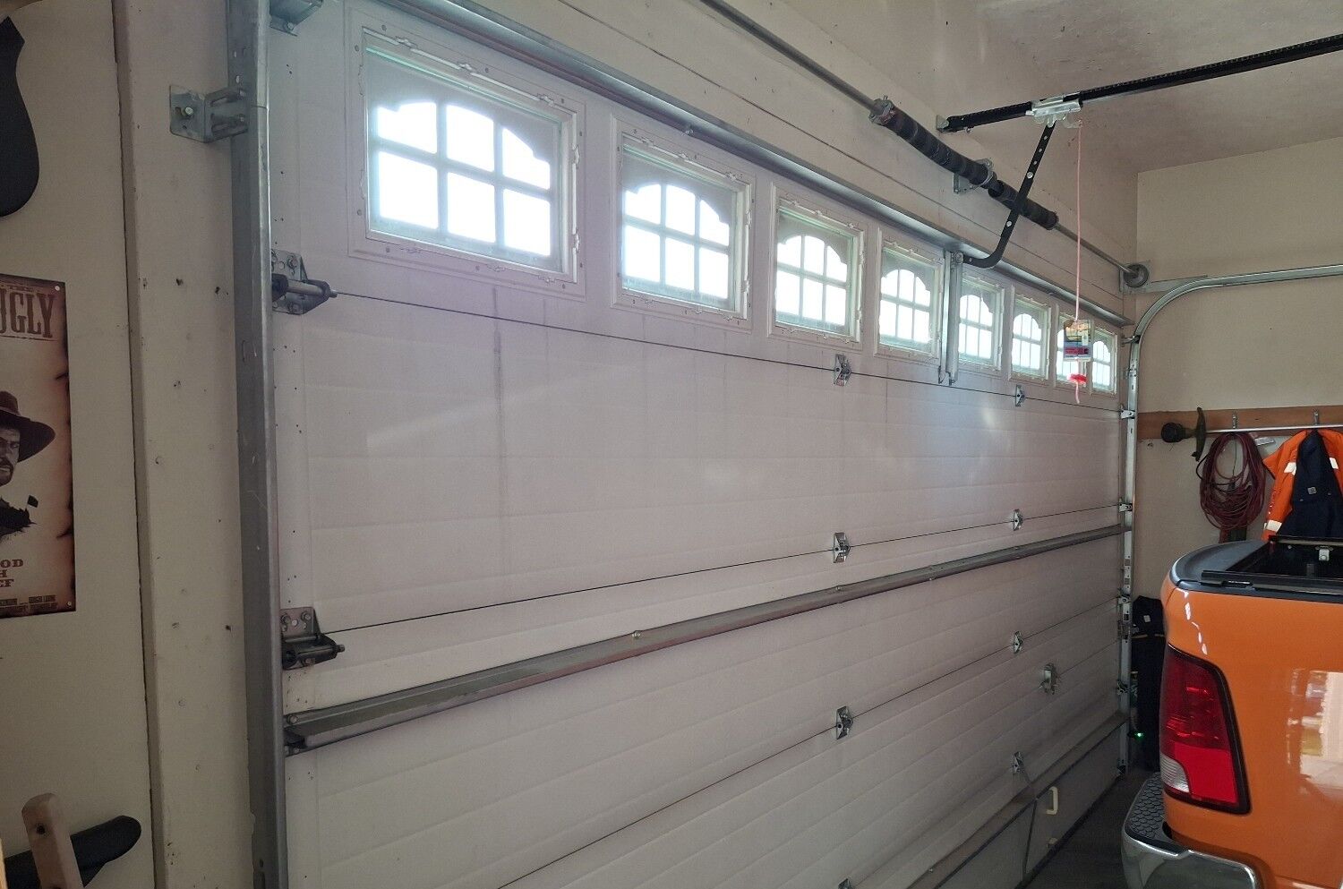 Interior view of a closed garage door with new black torsion spring is installed above the door.