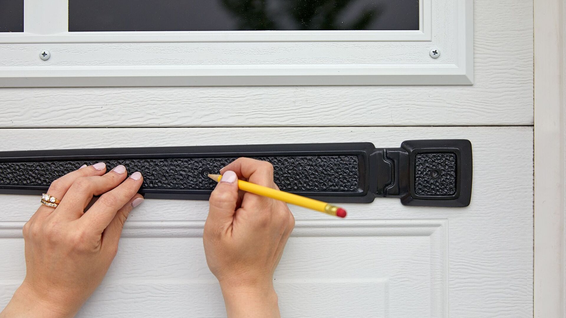 garage door service near me A homeowner installing garage door decorative hardware