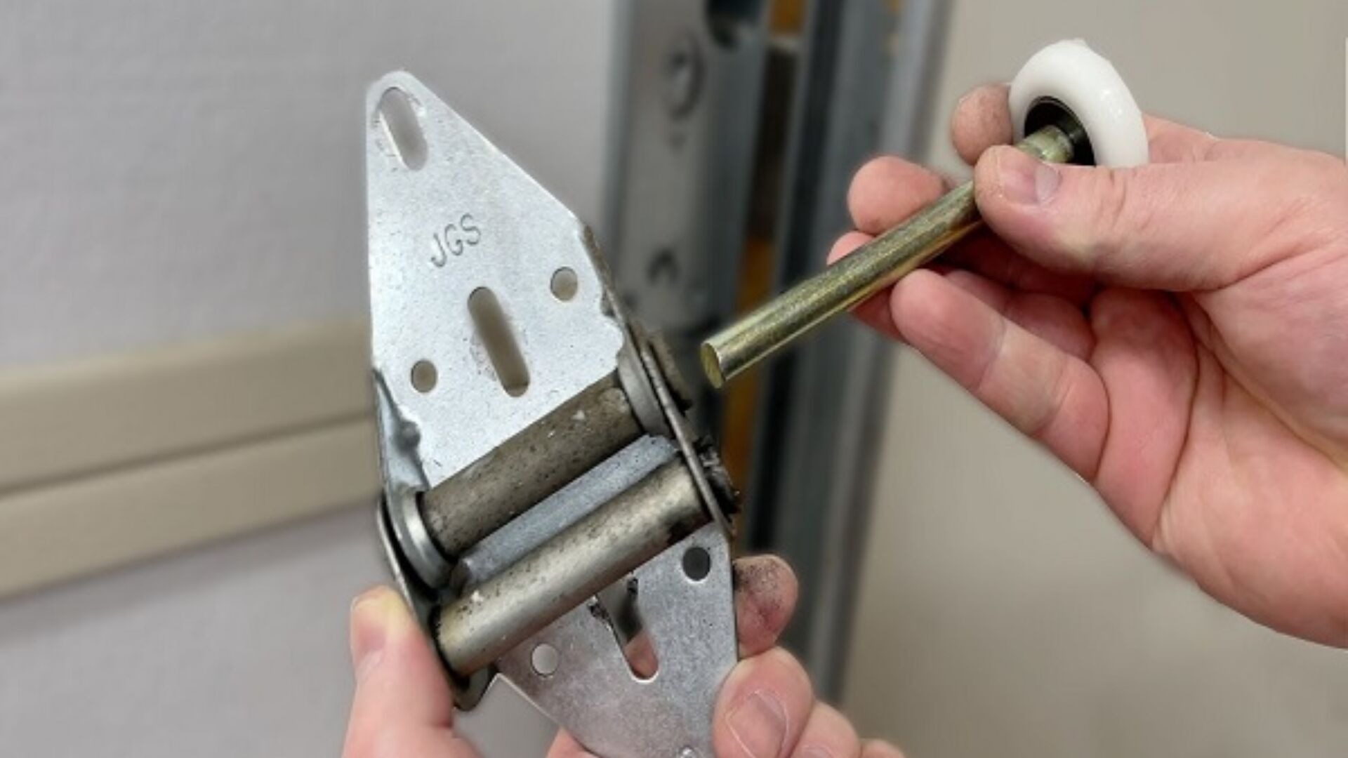 Technician holding a new nylon garage door roller for replacement work.