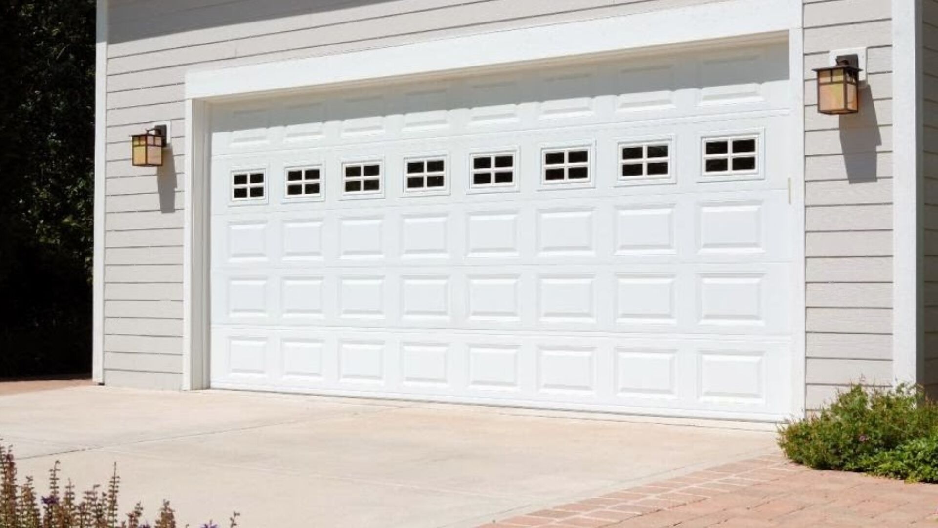 Front view of white steel garage door installed on light gray home exterior