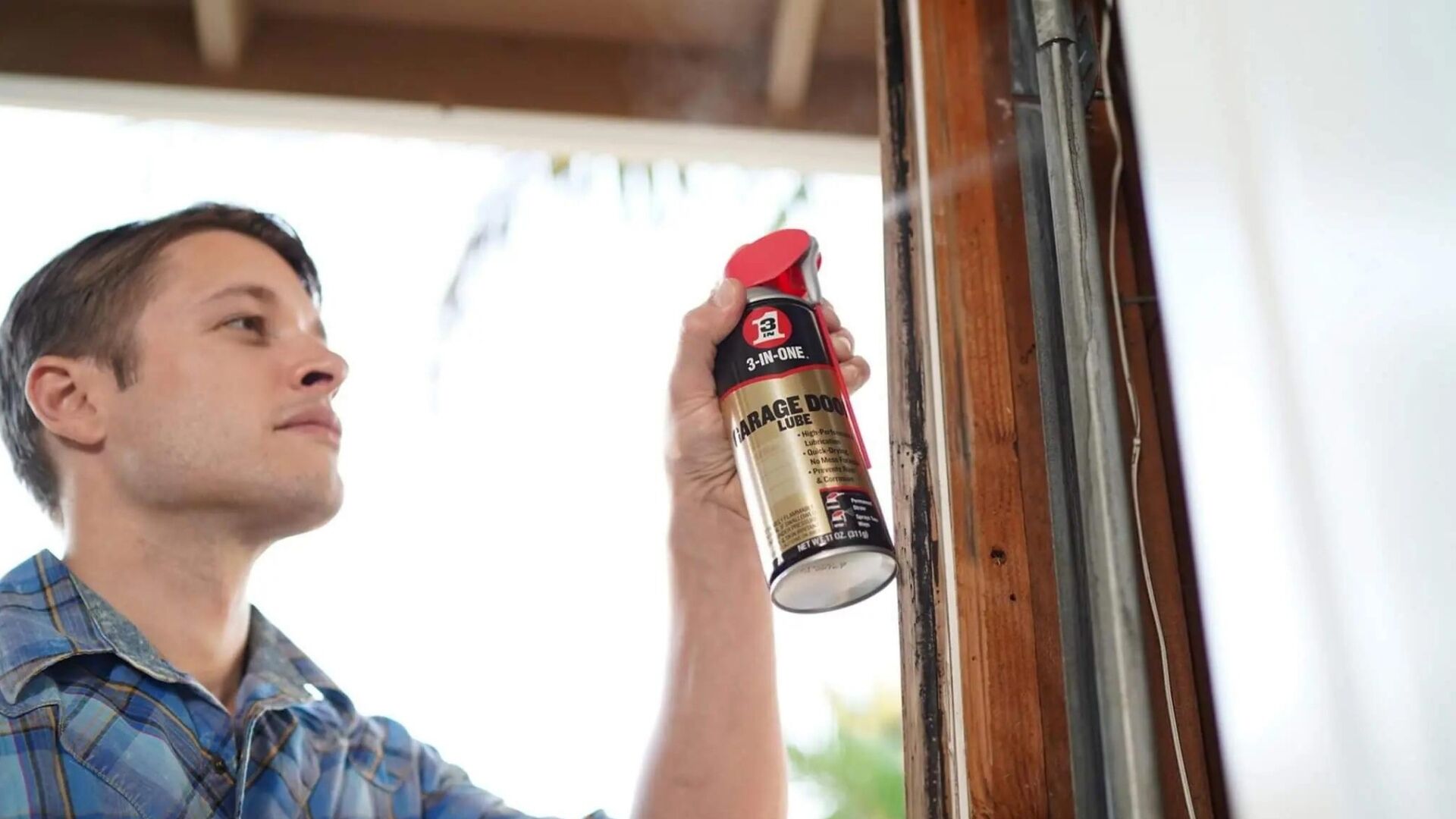 A man applying garage door lubricant on the tracks