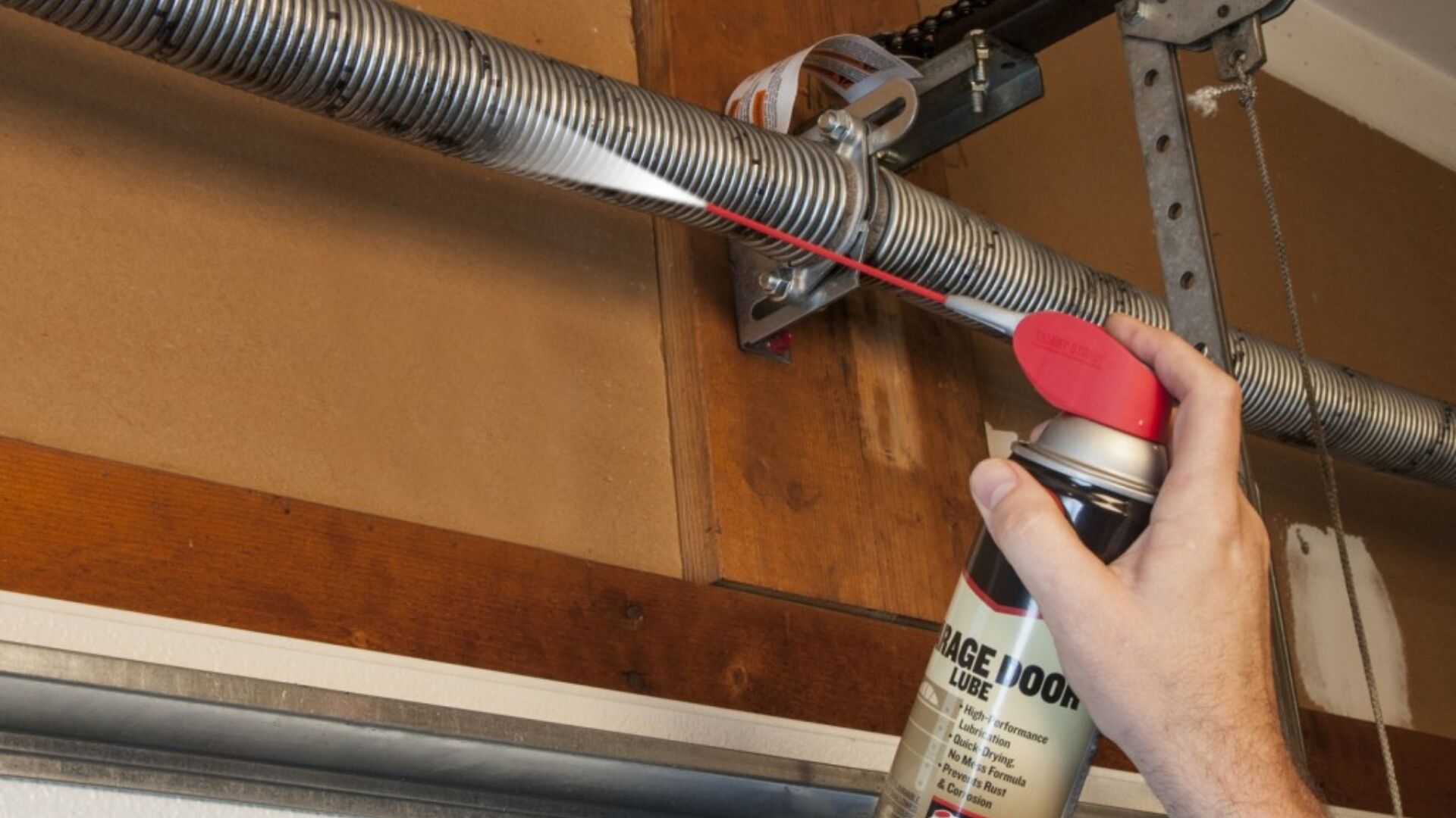 Using spray lubricant to reduce garage door spring friction and noise